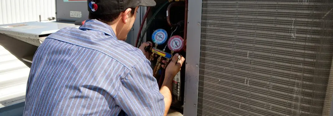 HVAC technician servicing a condenser unit in South Holland